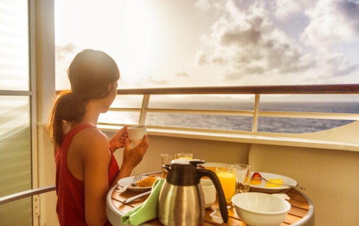 choosing the best stateroom location a Woman eating breakfast on a cruise ship balcony with ocean views