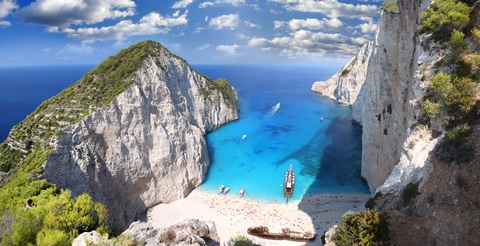 Aerial view of Navagio Beach on Zakynthos, Greece, with turquoise water, white cliffs, and the famous shipwreck on the sand.