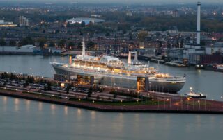 Large cruise ship docked in Rotterdam Harbor at dusk in the Netherlands, a popular embarkation point for the Netherlands by cruise journeys.