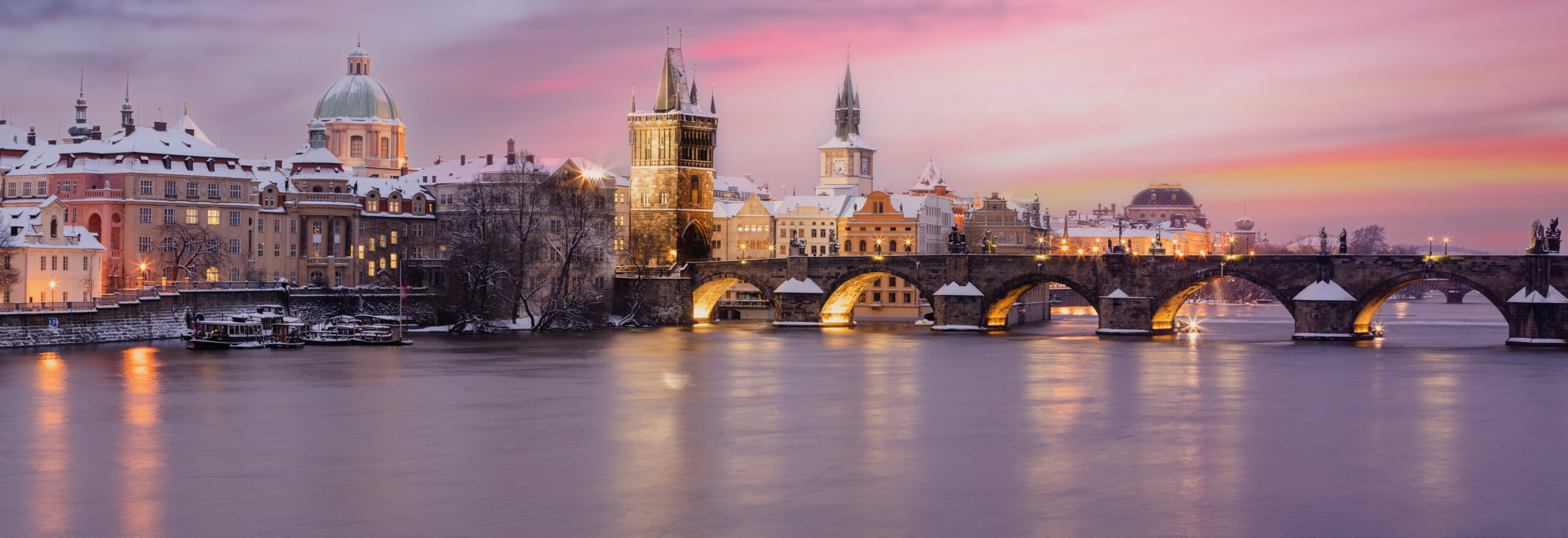 Charles Bridge, Prague in Winter Sunset A paddlewheel riverboat docked along the New Orleans waterfront at sunset, with the city skyline and historic French Quarter buildings glowing in warm golden light.