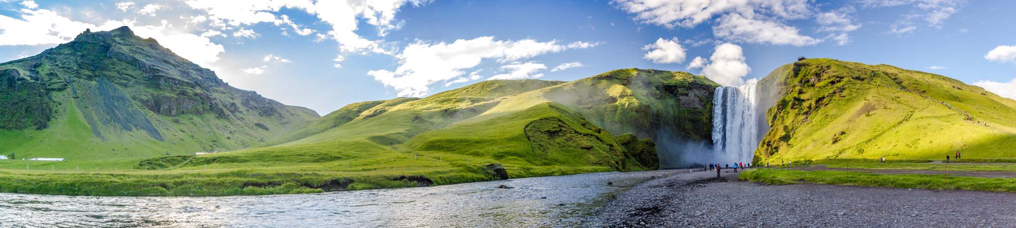 A majestic waterfall cascading down a lush green cliff in a scenic Icelandic landscape, with a river in the foreground and green mountains surrounding the waterfall.