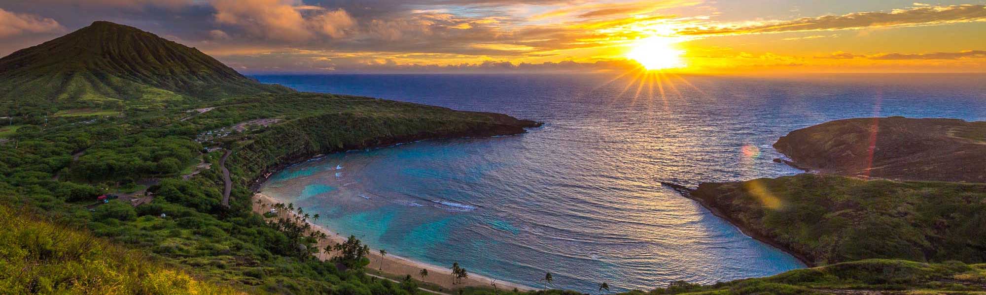 Waikiki Beach at Twilight with Diamond Head A stunning twilight view of Waikiki Beach, Hawaii, showcasing the iconic crescent shoreline lined with luxury high-rise hotels and resorts illuminated against the deepening blue sky. Diamond Head volcanic crater dominates the background, while palm-lined beaches and calm turquoise waters reflect the warm glow of evening lights along the bustling beachfront.