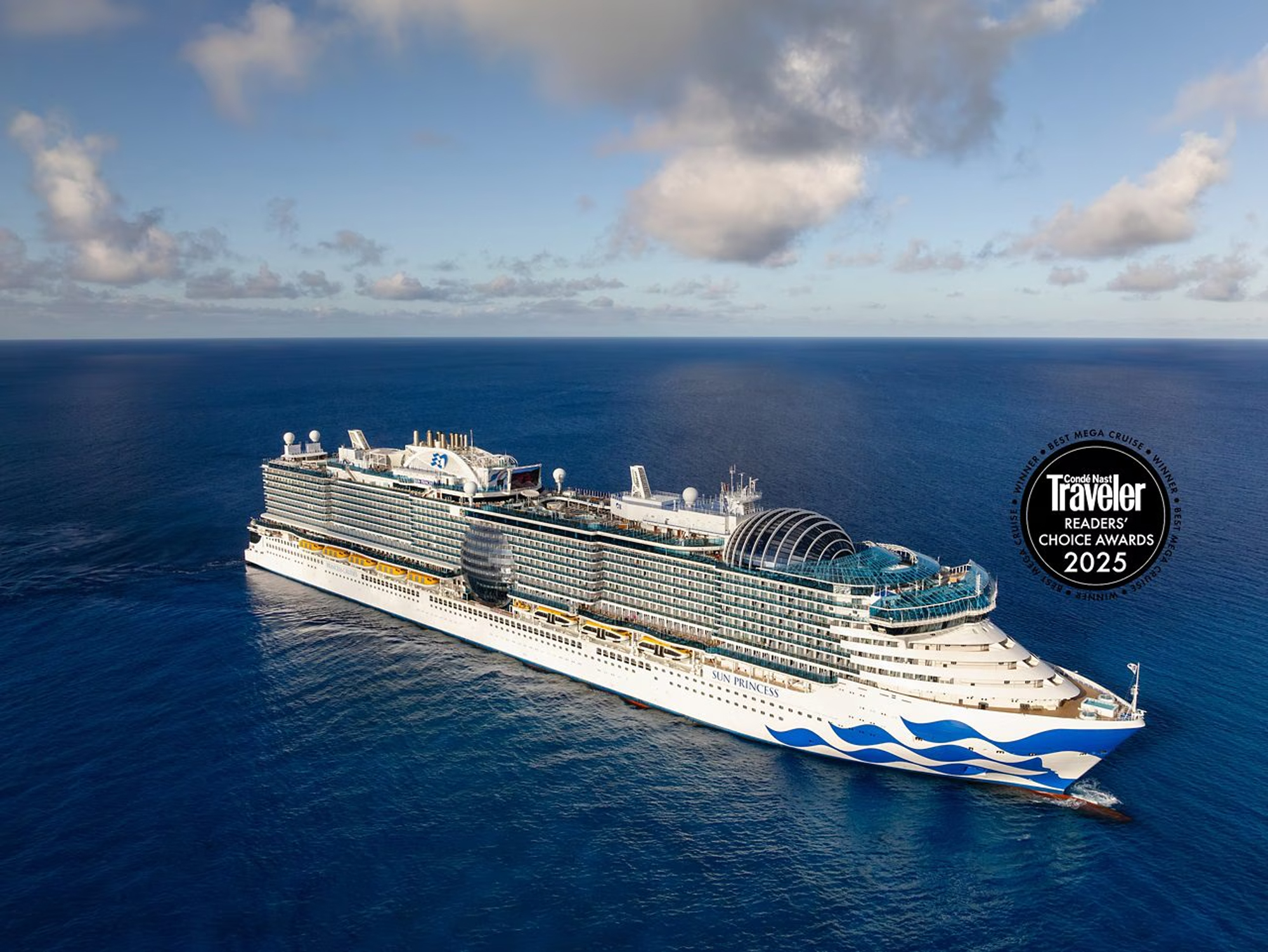 Sun Princess Mega Cruise Ship at Sea A modern mega cruise ship sails through calm, deep blue waters under partly cloudy skies. The vessel features distinctive white hull with blue wave livery, multiple decks with visible cabin windows, towering funnels, and expansive deck structures, exemplifying contemporary luxury cruise ship design.