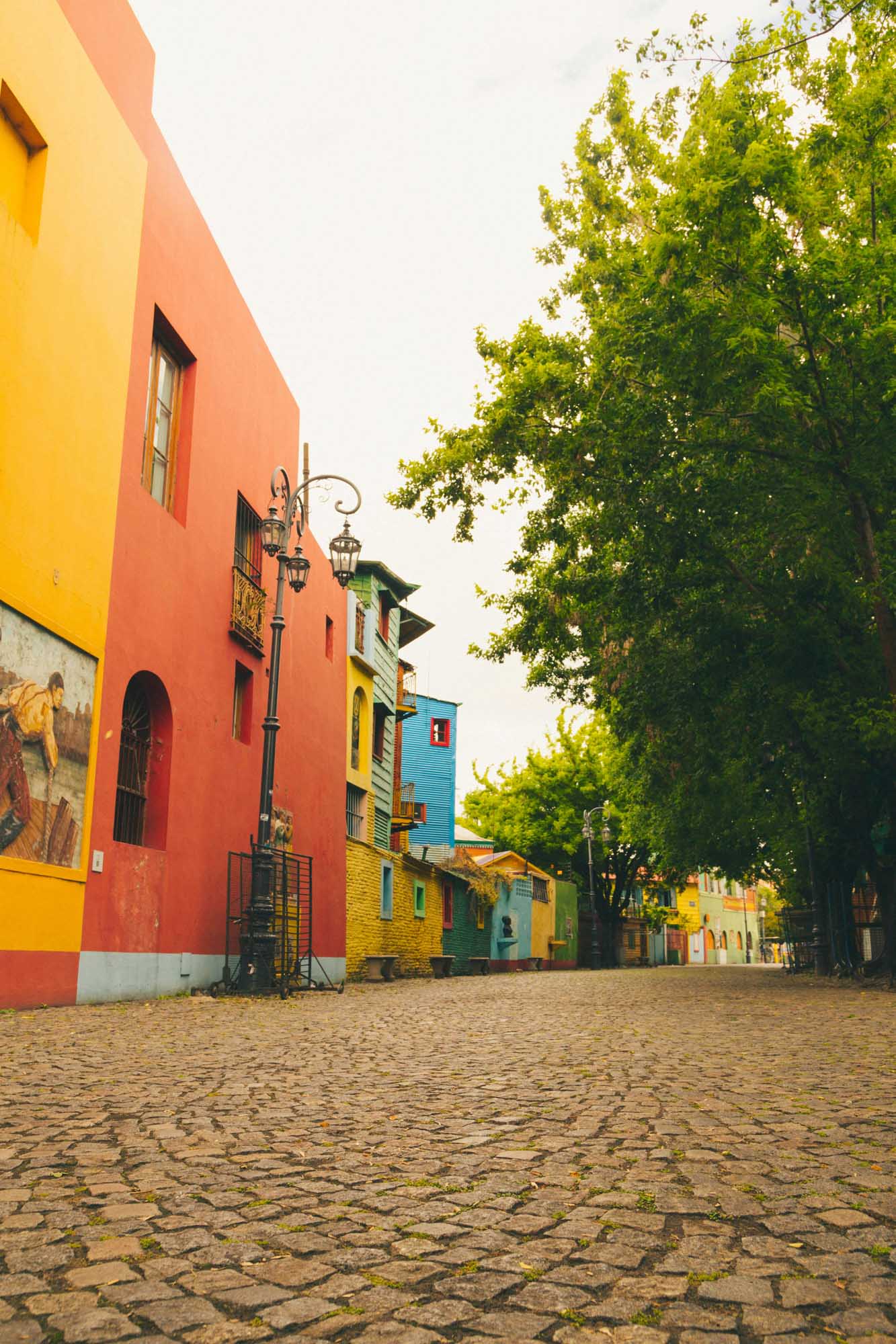 A vibrant cobblestone street lined with brightly painted colonial buildings in shades of red