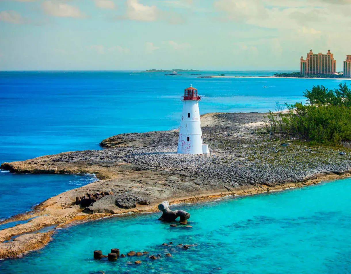 A scenic coastal view featuring a distinctive white and red lighthouse standing on a rocky
