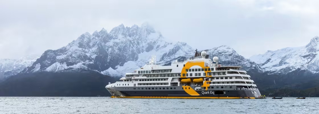 A striking expedition cruise ship with distinctive yellow and white hull markings navigates