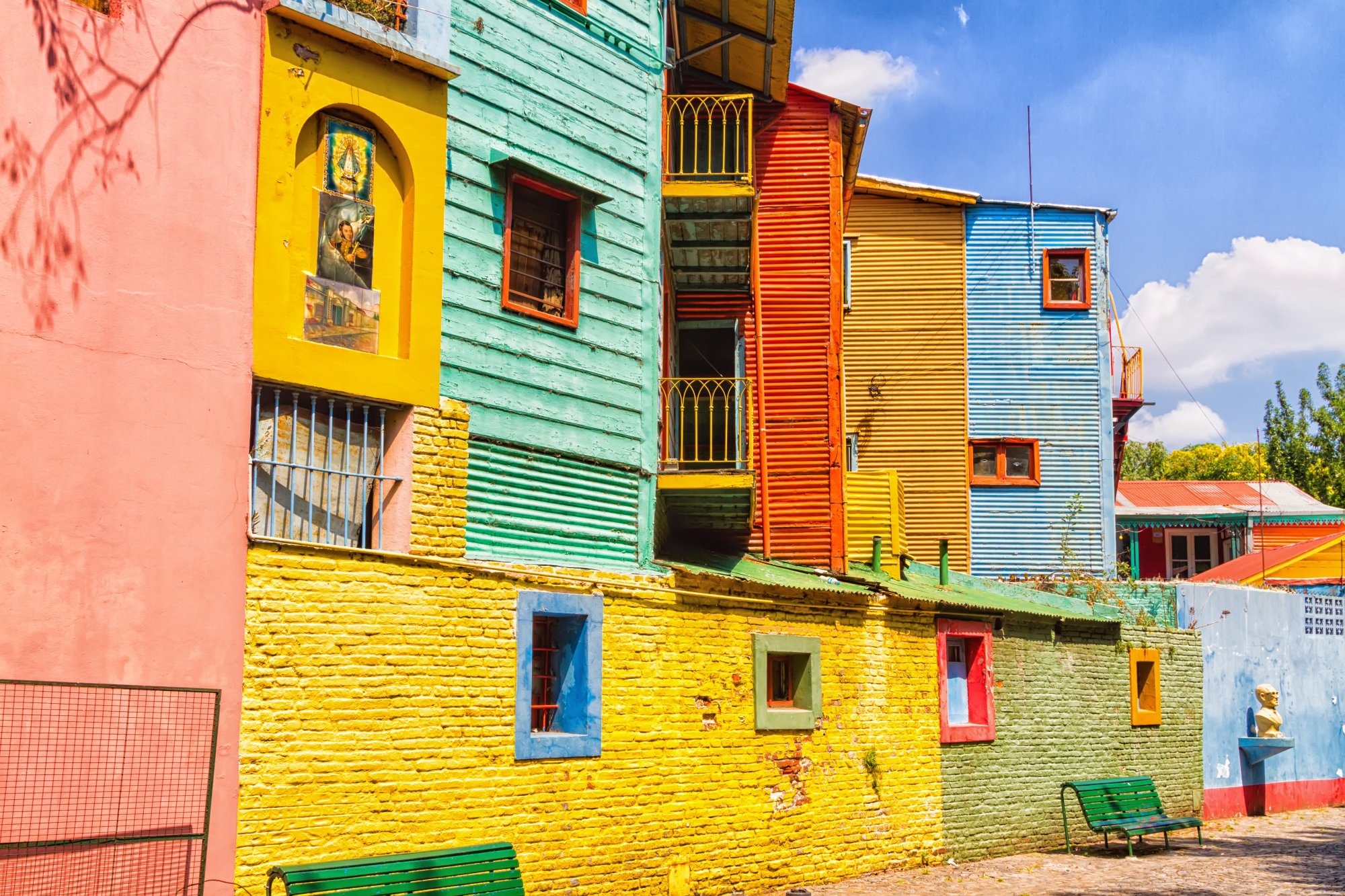 A vibrant street scene showcasing the iconic pastel-colored corrugated metal buildings of La Boca