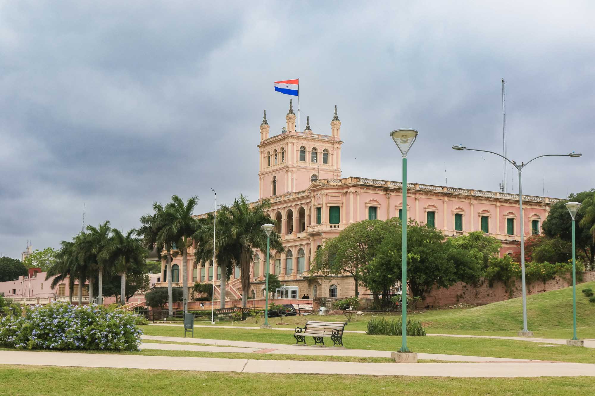 A stunning pink neoclassical government palace with multiple spires and a Paraguayan flag flying