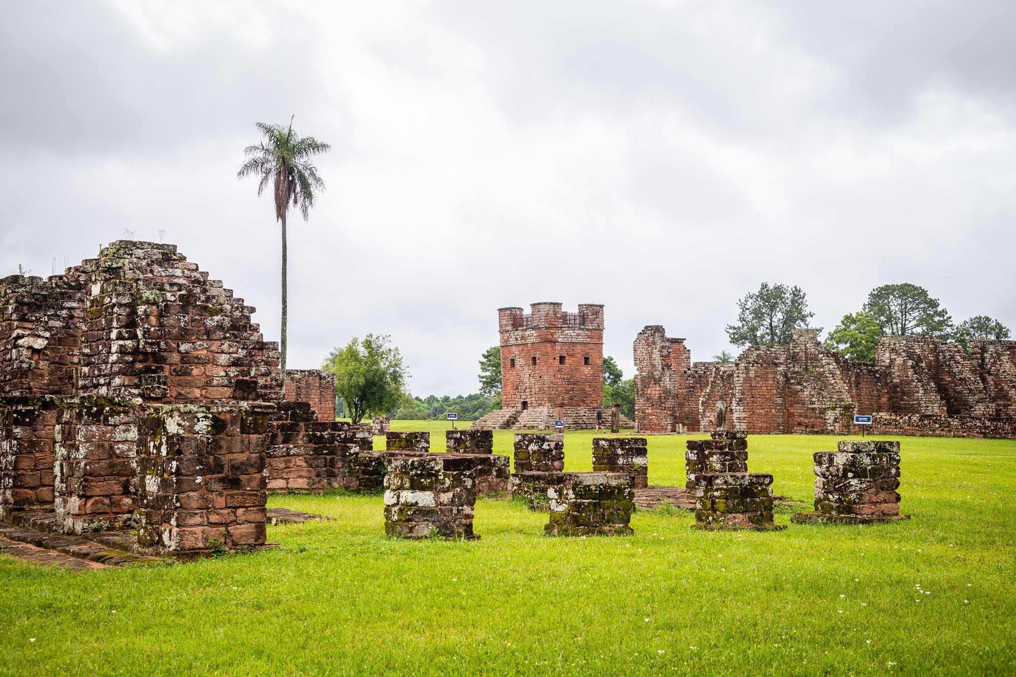 Ancient brick ruins of the Santísima Trinidad Monastery spread across a verdant green field