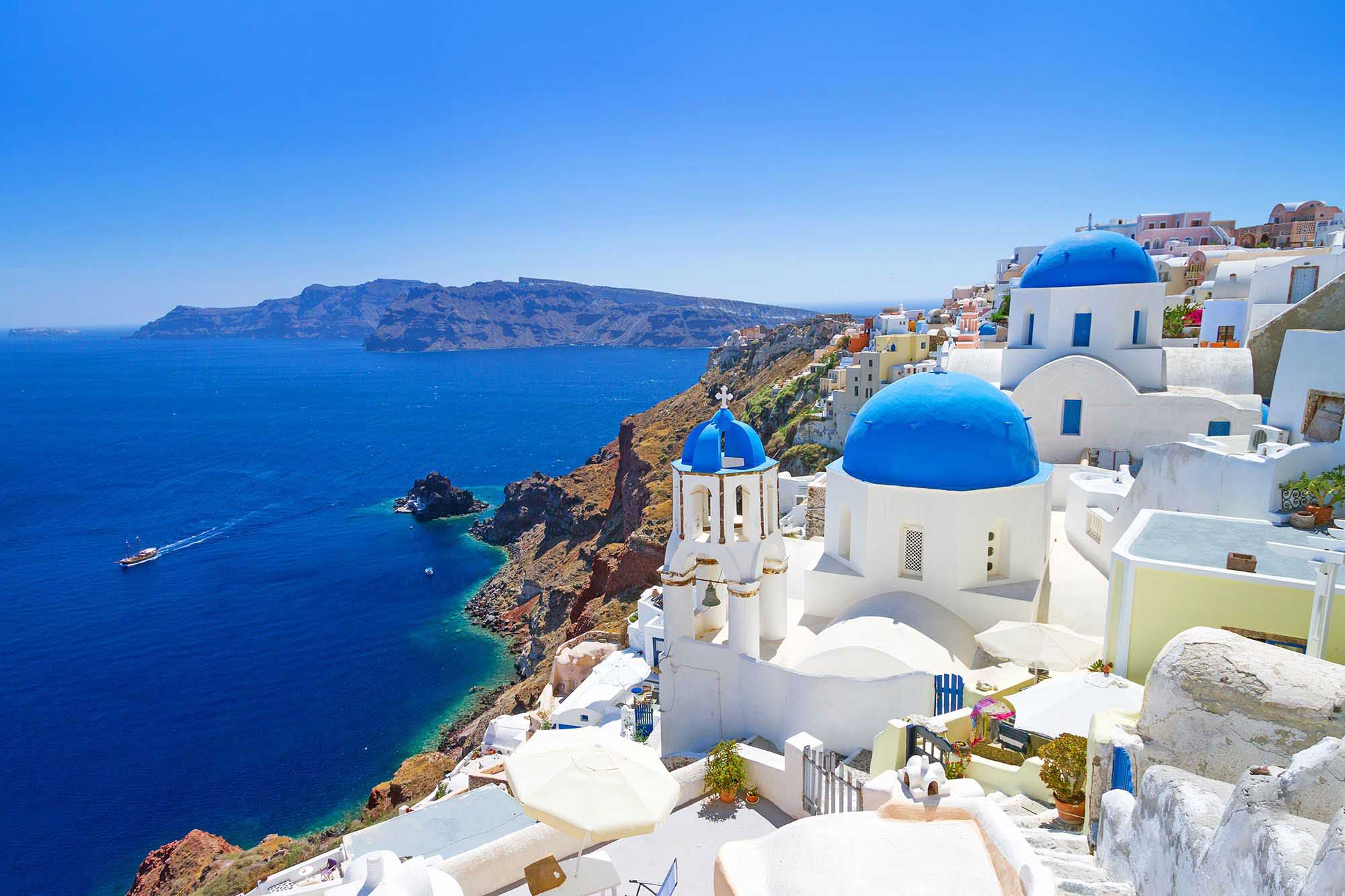 Santorini cliffside village featuring white buildings and iconic blue-domed churches overlooking the Aegean Sea