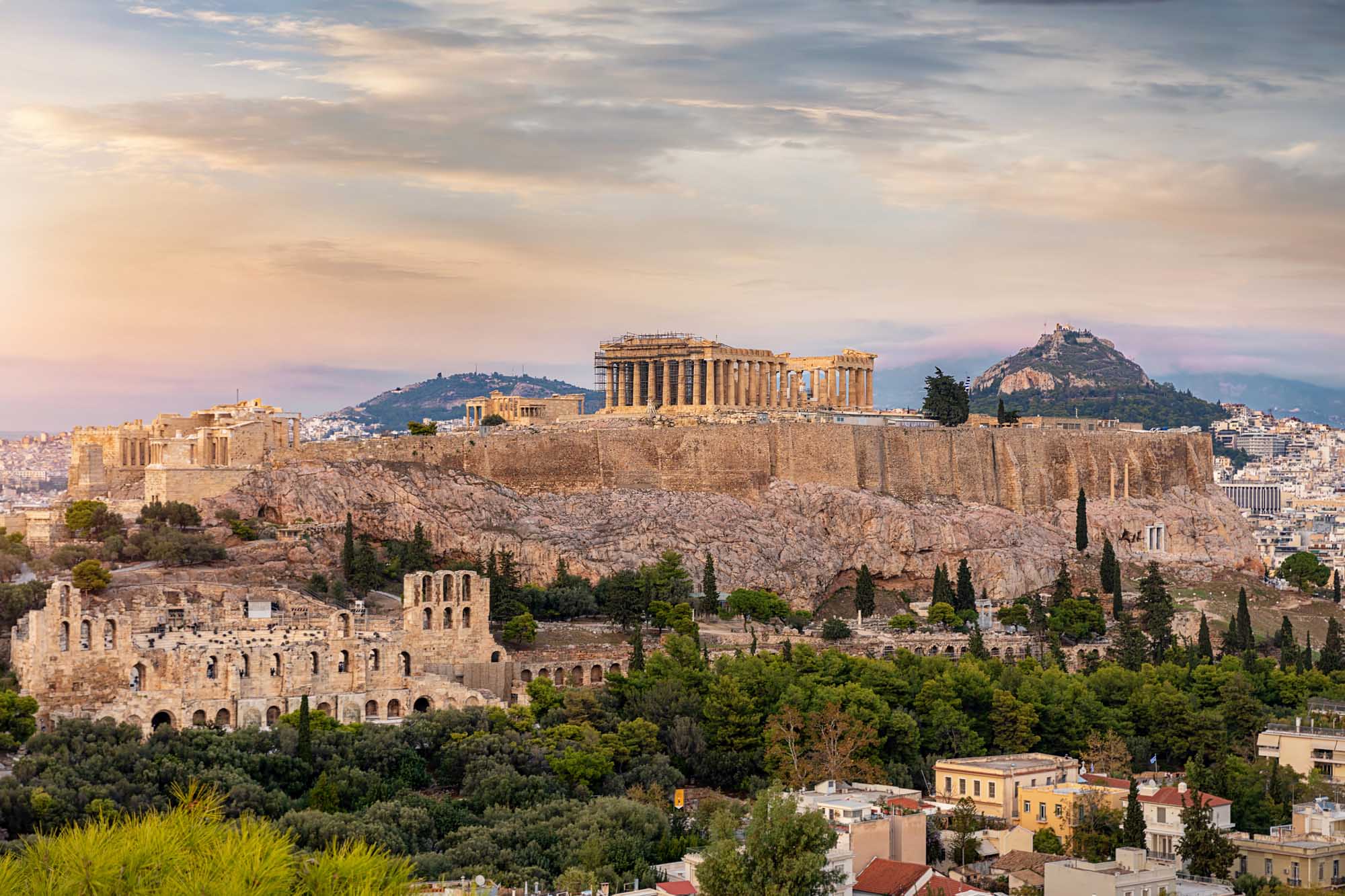 A stunning panoramic view of the iconic Acropolis with the Parthenon dominating the hilltop, bathed in golden hour light
