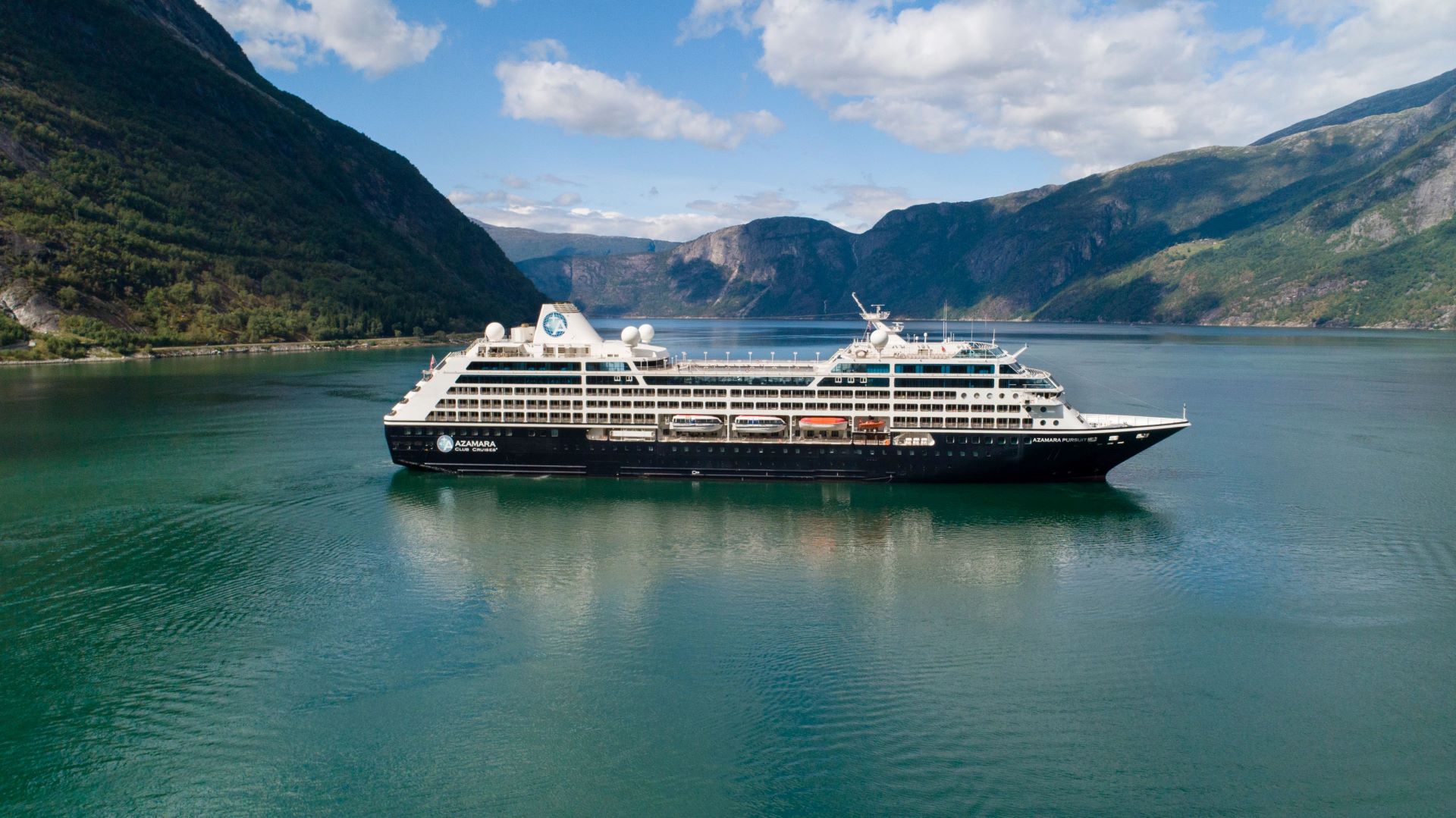 The Azamara cruise ship anchored in a pristine Norwegian fjord surrounded by towering cliff faces