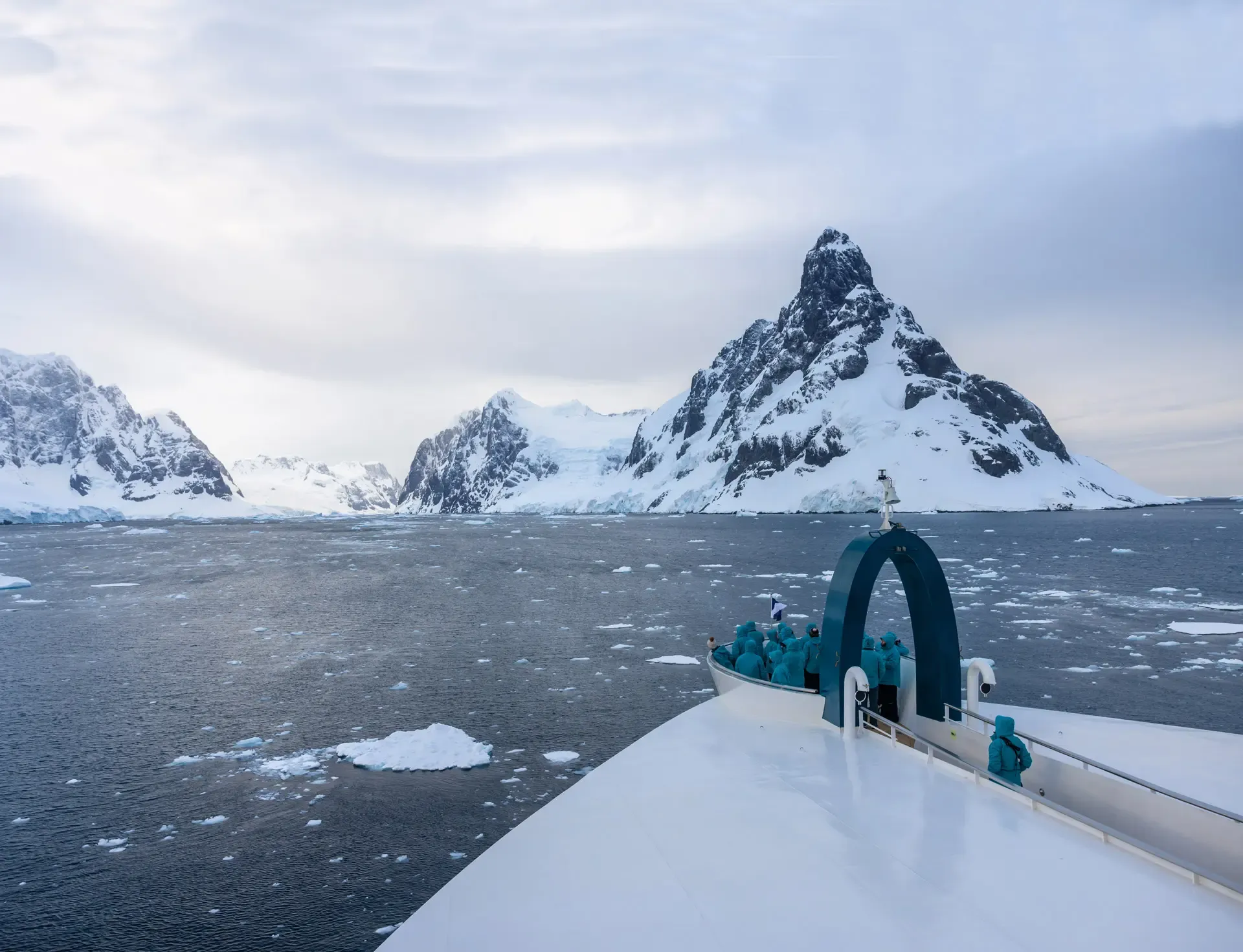 Passengers on expedition ship observe dramatic snow-capped Antarctic peaks and icy waters