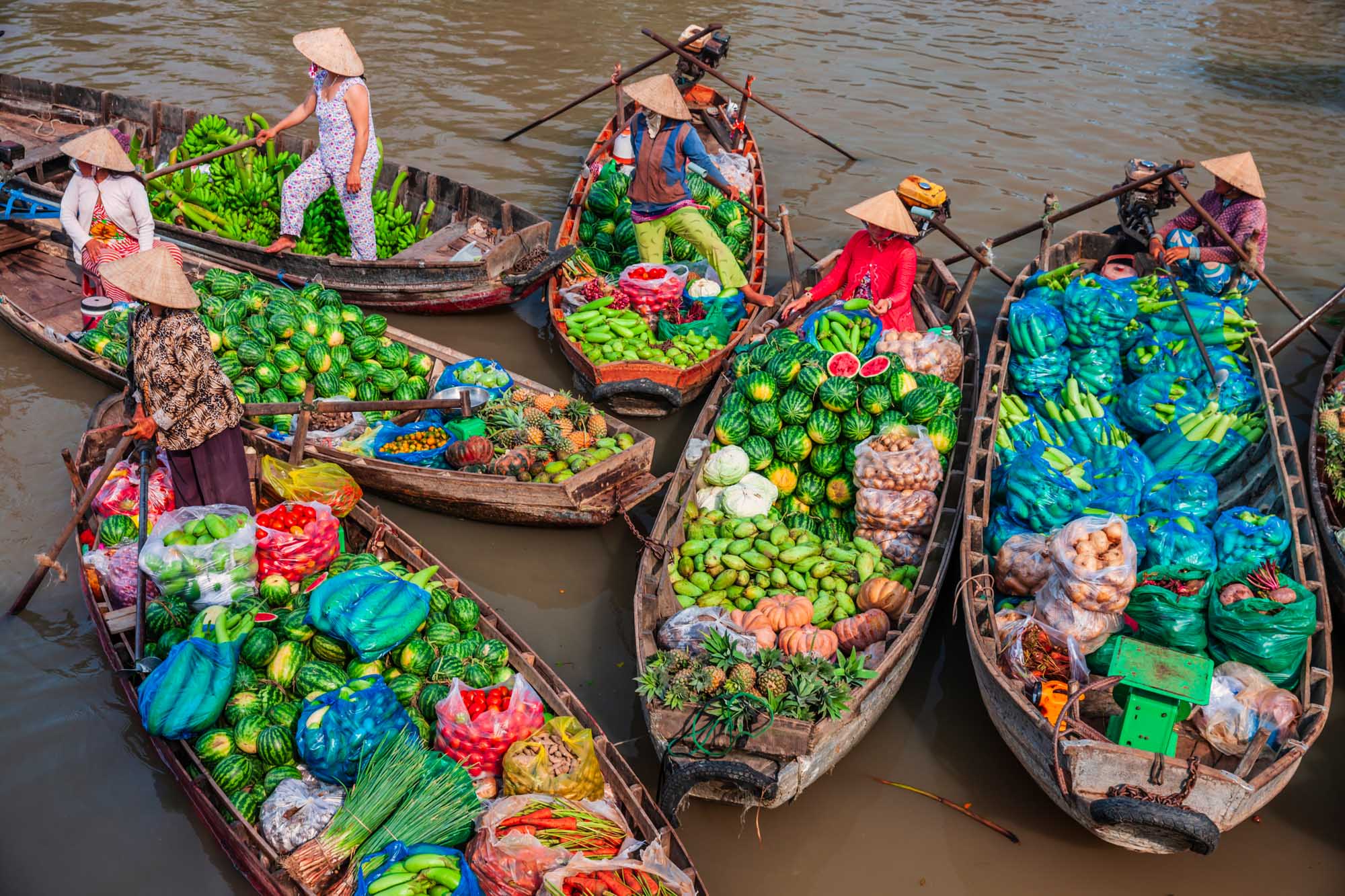 Floating Market Vendors on Mekong River Delta Vietnamese vendors in traditional conical hats navigate wooden boats laden with vibrant fresh