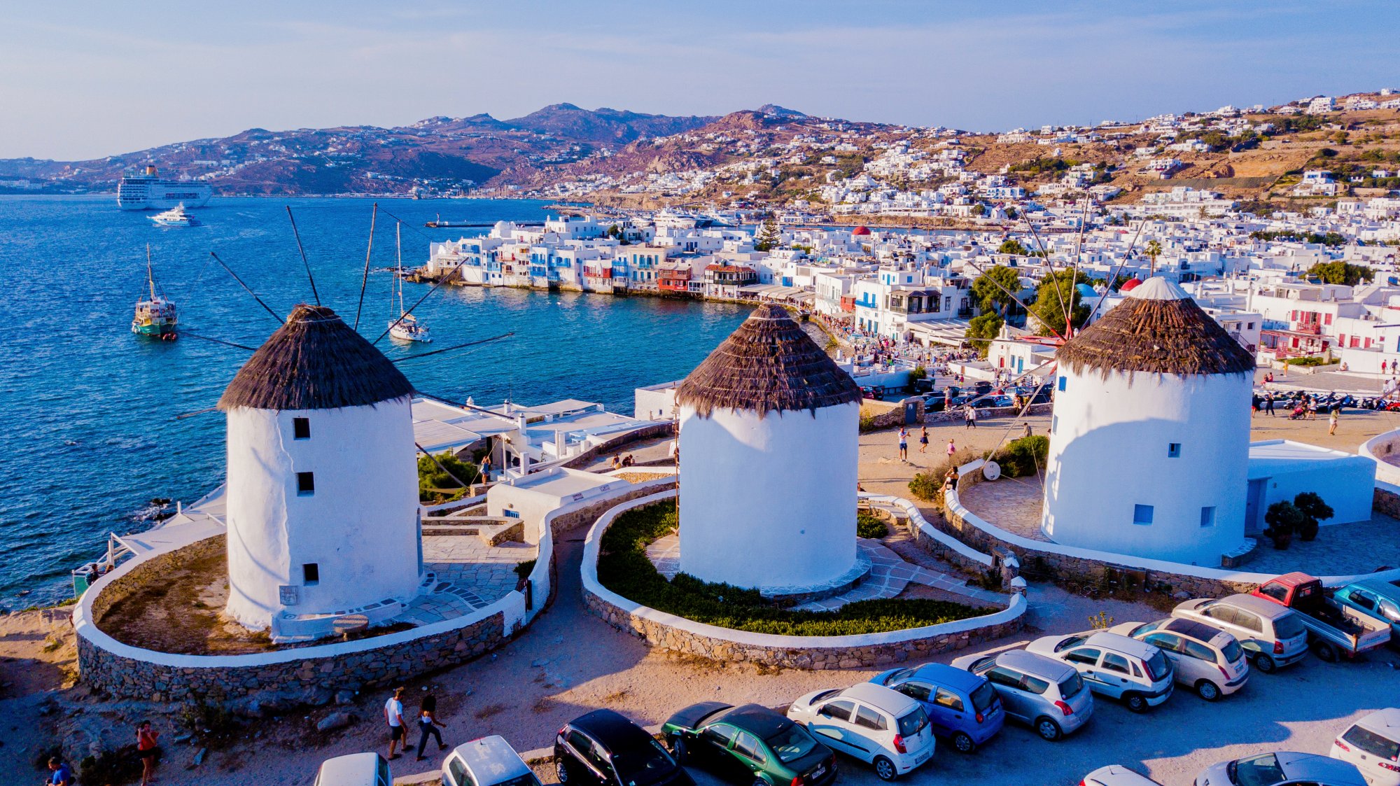 A picturesque view of Mykonos's iconic white-washed windmills with thatched roofs overlooking