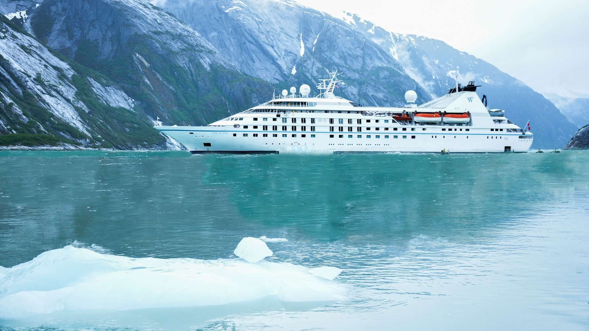 Luxury Cruise Ship in Alaskan Glacier Bay Luxury cruise ship anchored in turquoise waters of Glacier Bay with icebergs and snow-capped mountains