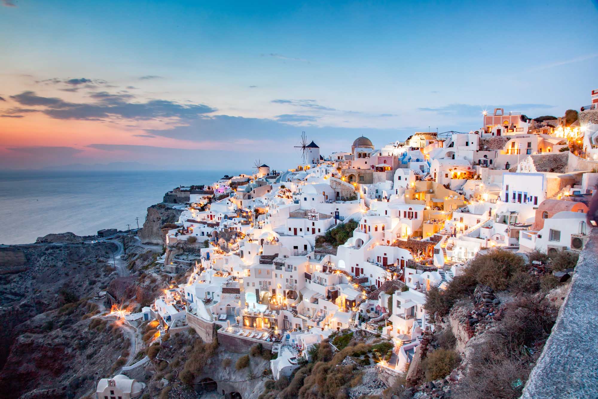 A stunning twilight view of Oia, Santorini's iconic cliffside village, with whitewashed buildings