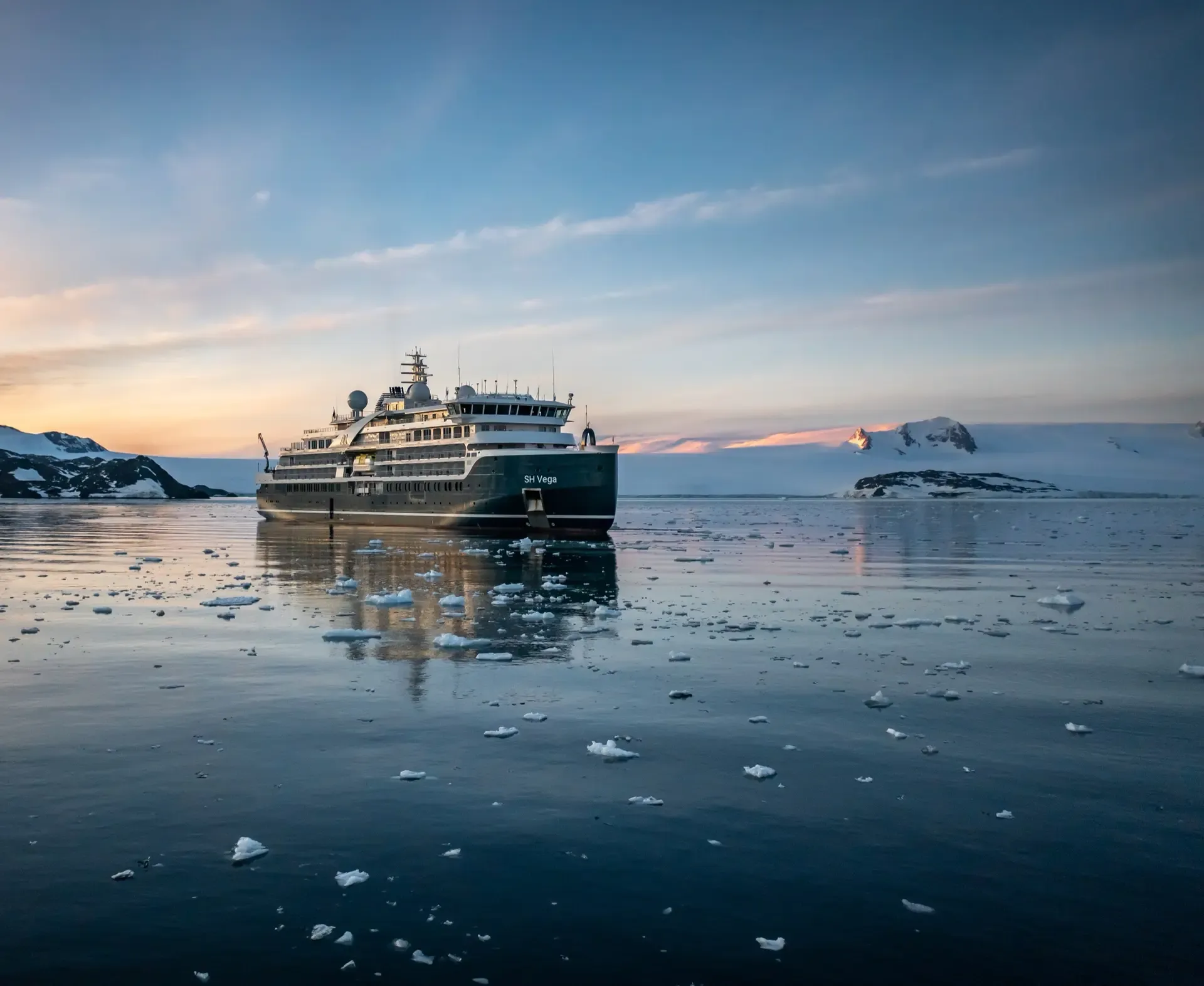 Seabourn Venture navigates icy Antarctic waters at sunset with snow-capped peaks visible