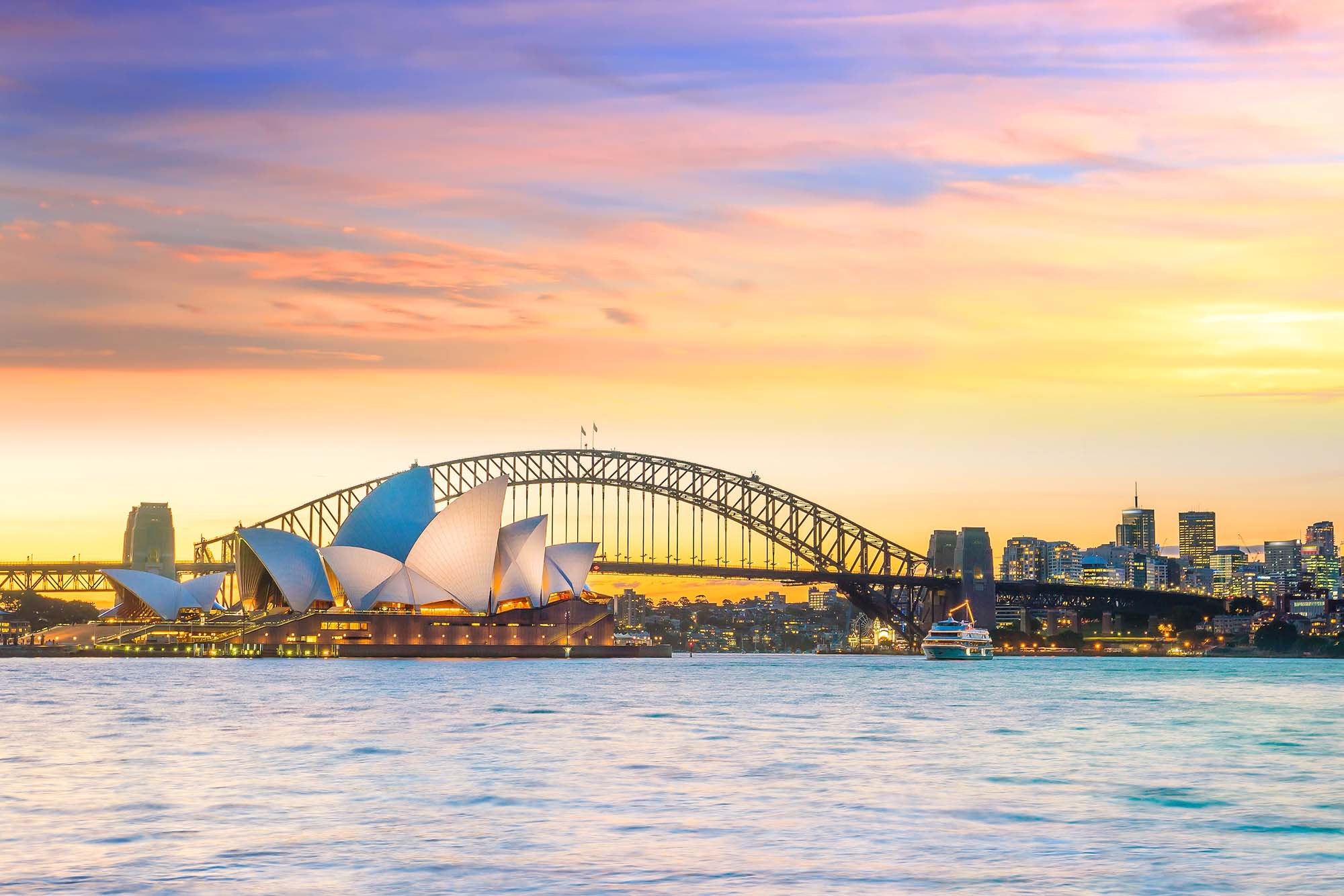 An iconic view of Sydney's most famous landmarks illuminated during golden hour, featuring