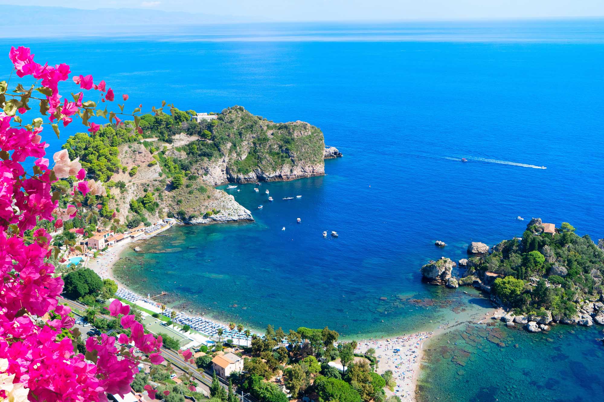 A stunning coastal view of Taormina's picturesque beach nestled beneath dramatic cliffs, with Isola