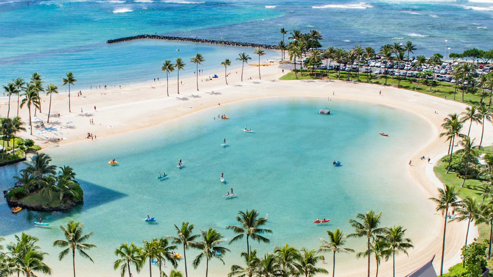 Aerial view of a pristine tropical lagoon with turquoise waters, white sandy beach, and palm trees