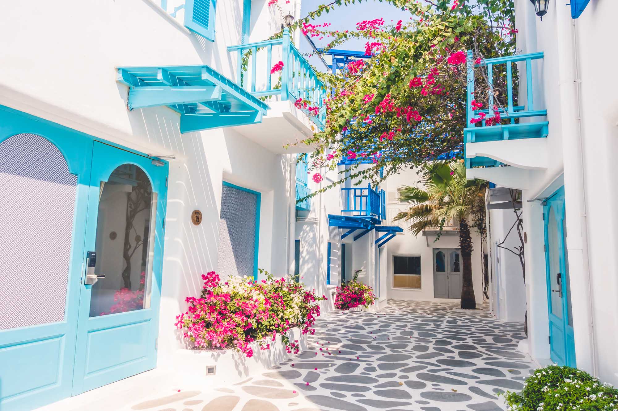 A stunning whitewashed Mediterranean courtyard featuring brilliant turquoise-blue doors, railings
