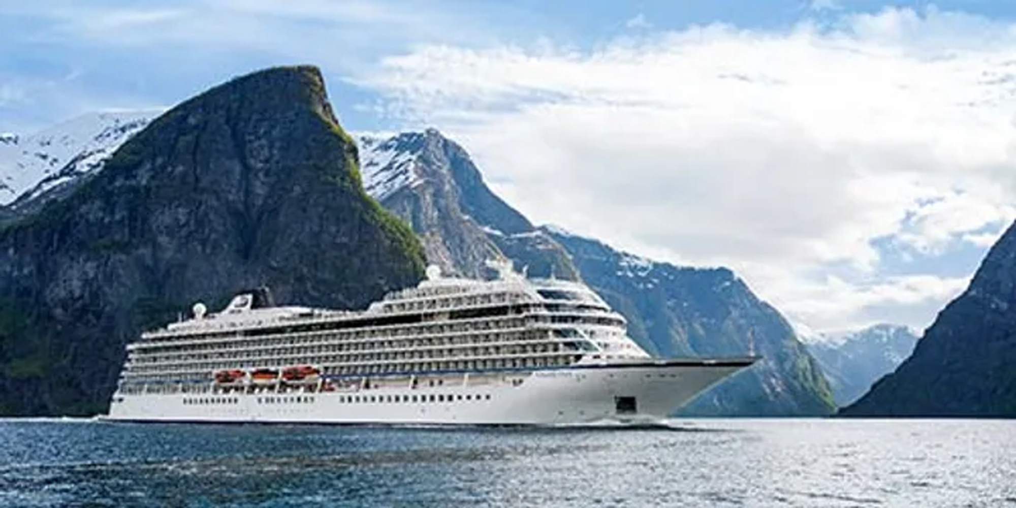 Viking Cruise Ship in Norwegian Fjord A large modern cruise ship navigates through a dramatic Norwegian fjord surrounded by towering snow-capped mountains