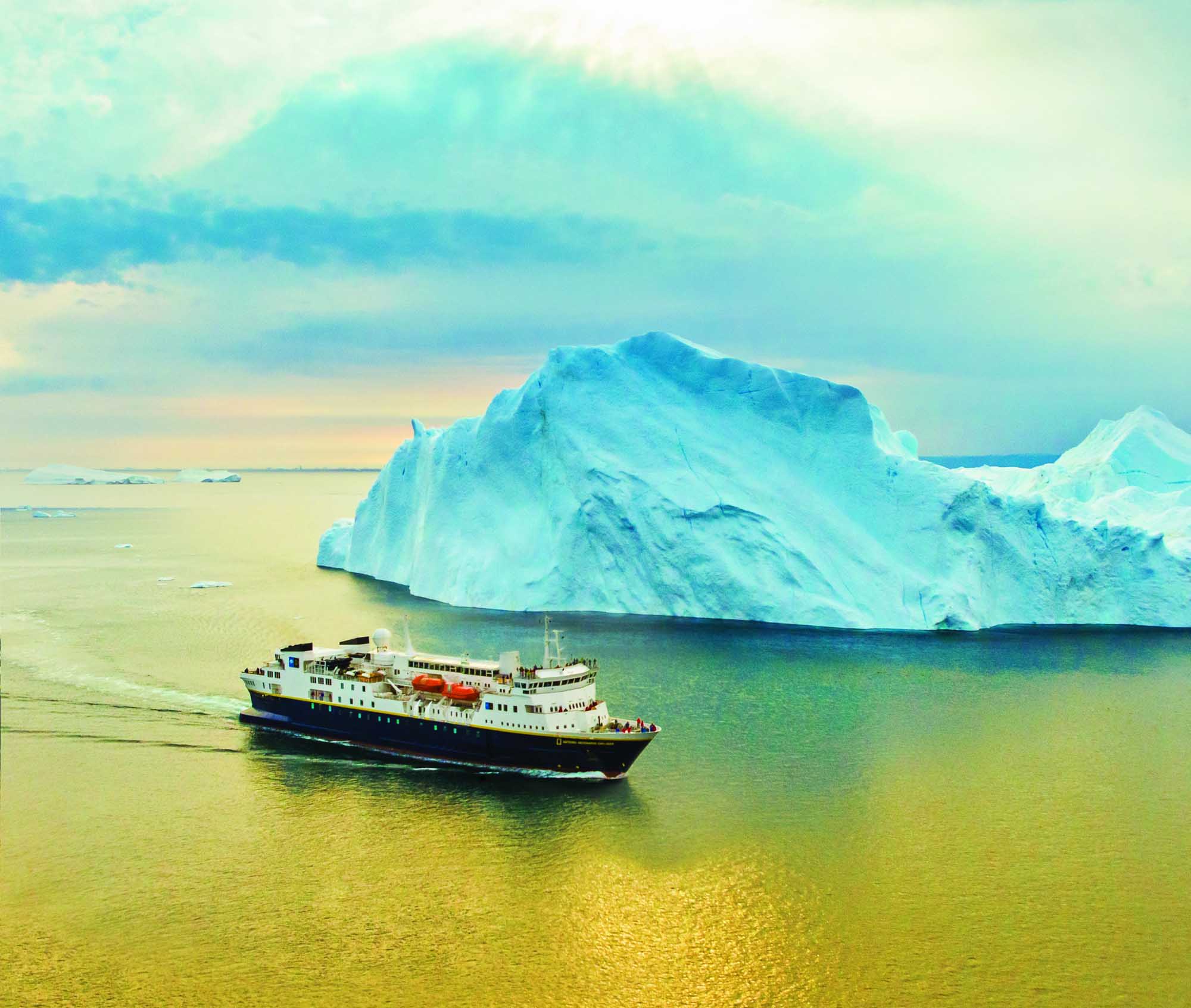 Expedition Ship at Greenland Iceberg A small expedition cruise vessel navigates near a massive turquoise iceberg in Greenland waters