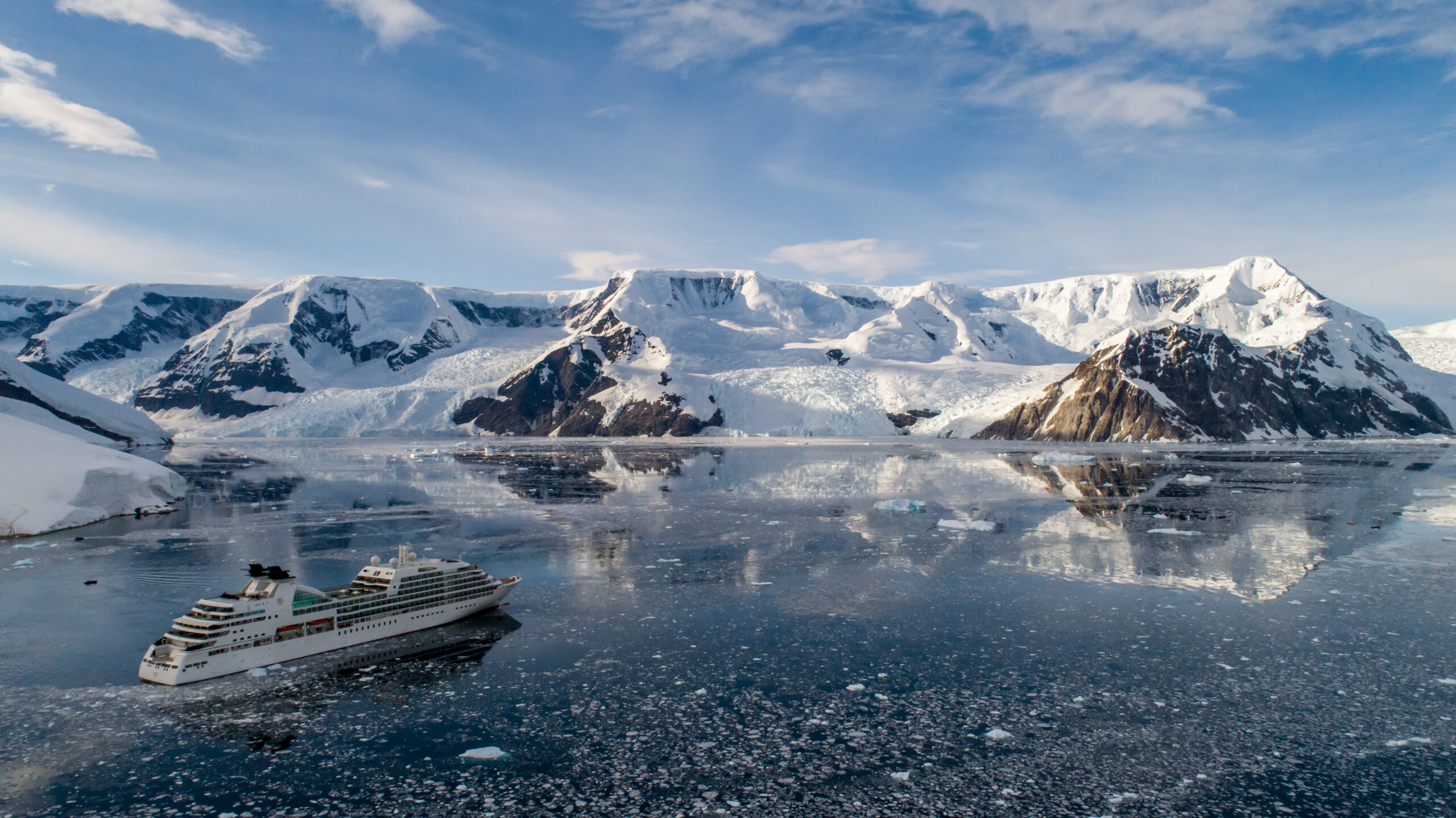 Luxury Cruise Ship in Antarctic Harbor A modern expedition cruise ship navigates through icy Antarctic waters surrounded by snow-capped