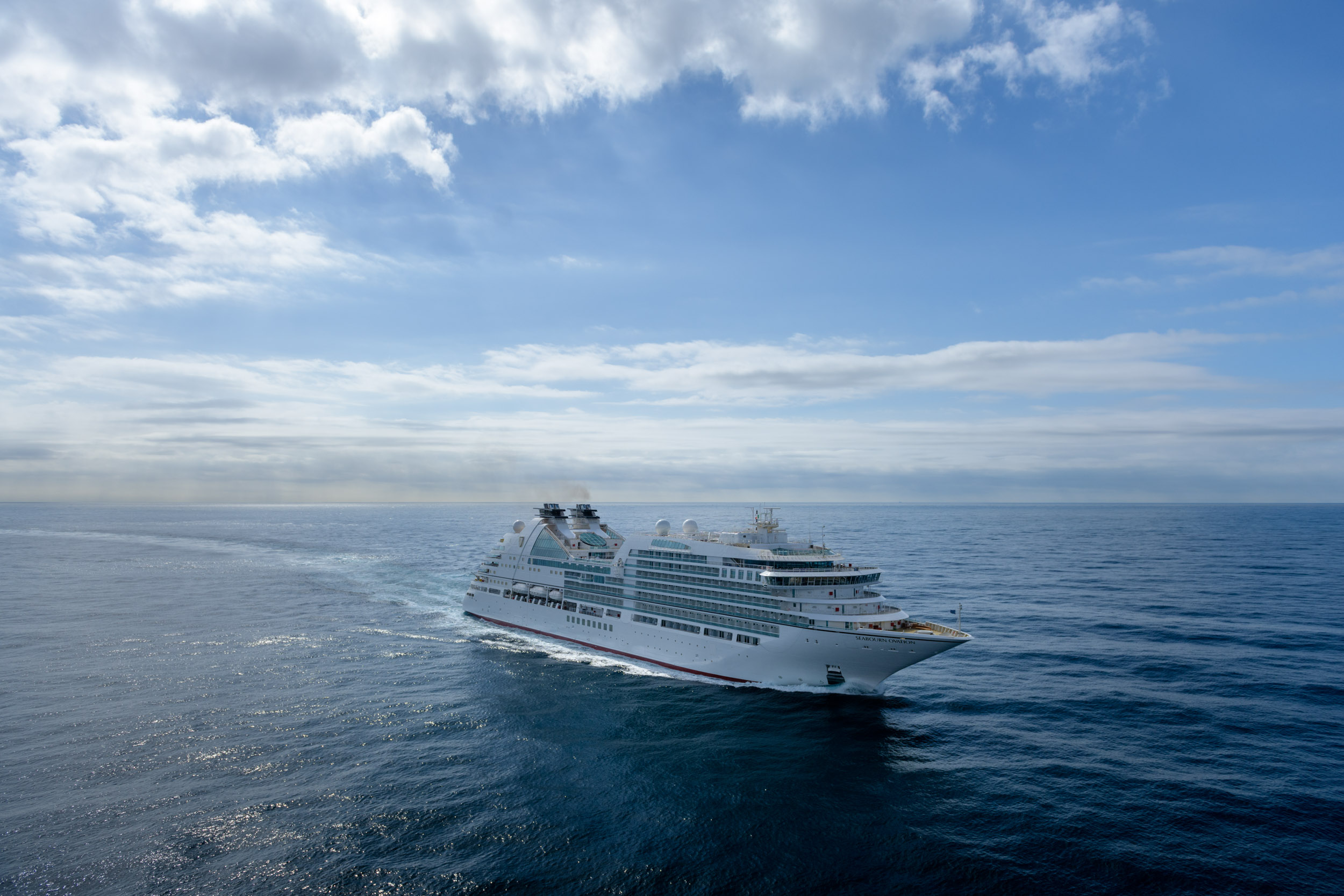 Seabourn Ovation Cruise Ship at Sea A luxurious Seabourn Ovation cruise ship sailing through calm blue waters under a partly cloudy