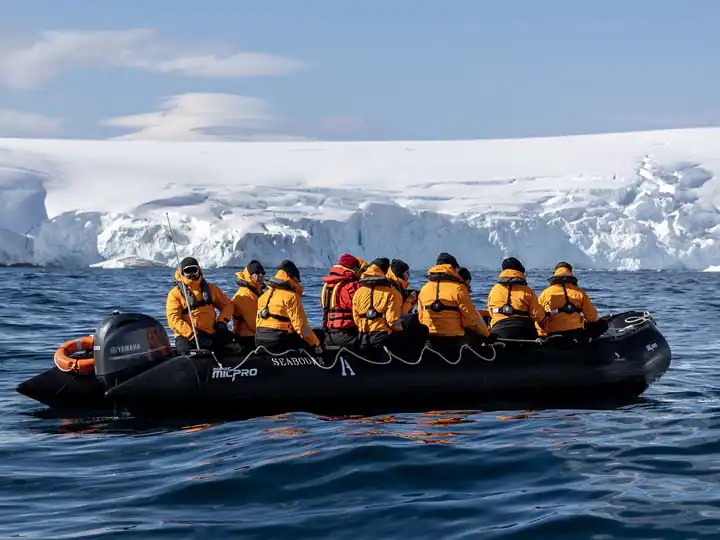 Seabourn Pursuit Zodiac Excursion in Antarctica Passengers in a black Zodiac inflatable boat wearing yellow and red life jackets navigate Antarctic