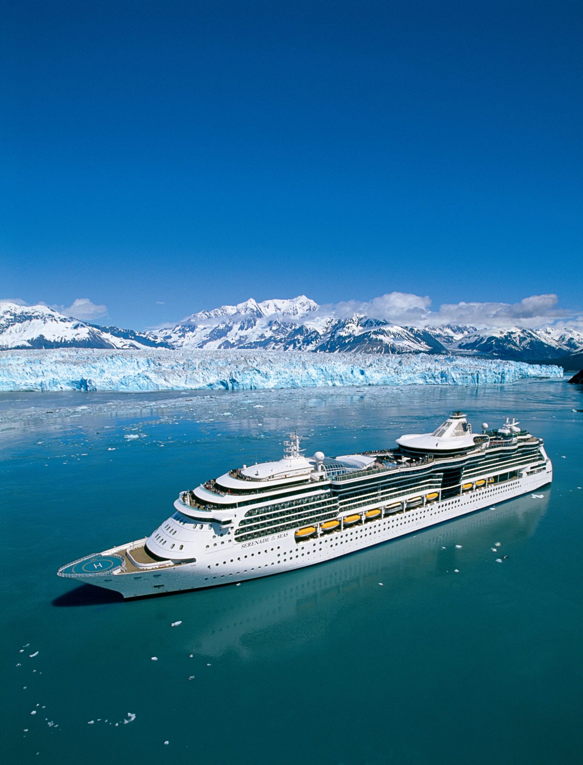 A large modern cruise ship, the Serenade of the Seas, navigates the turquoise glacial waters near