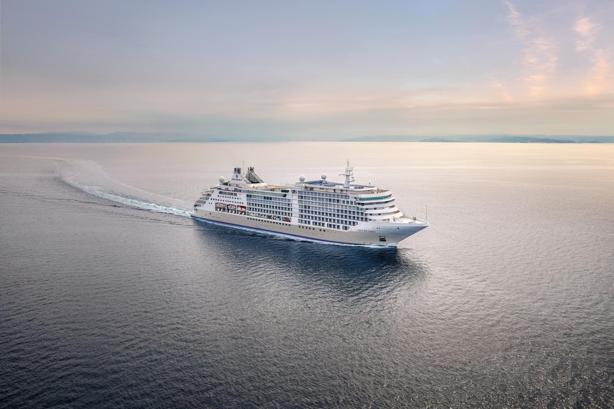 Silversea Luxury Cruise Ship at Sea A modern Silversea luxury cruise ship navigates calm waters with distant mountains visible on
