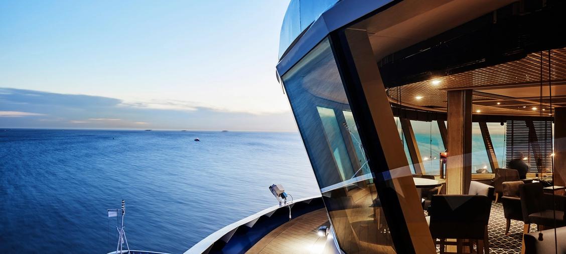 Silversea Luxury Suite with Ocean View at Dusk An elegant stateroom aboard a Silversea cruise ship featuring floor-to-ceiling windows overlooking