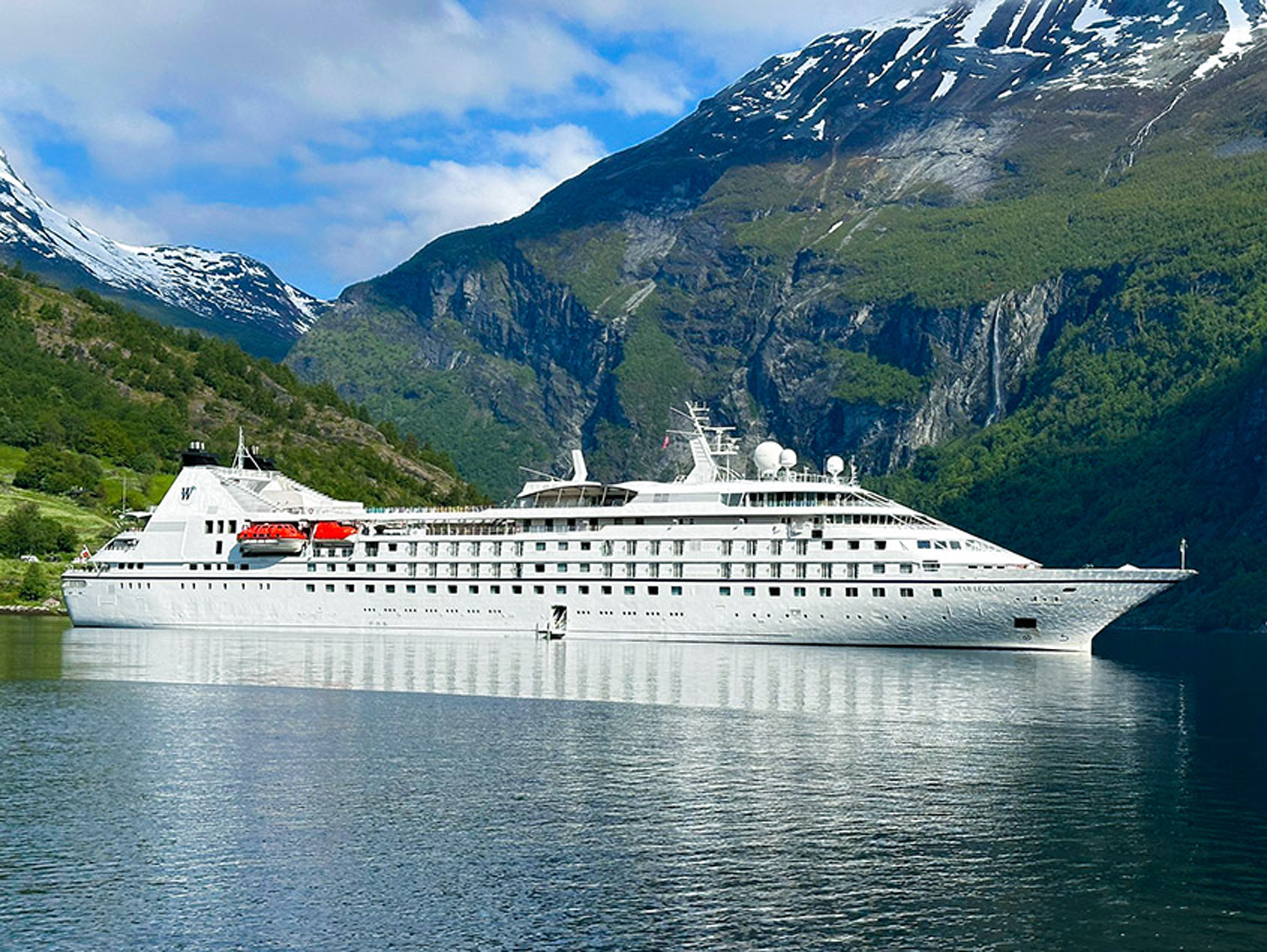 Star Legend Cruise Ship in Norwegian Fjord A luxury cruise ship navigates through a dramatic Norwegian fjord surrounded by snow-capped