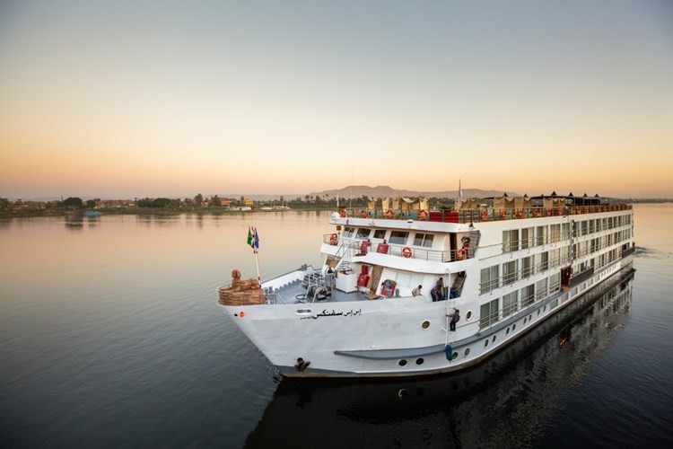 A luxurious river cruise ship with white hull and multi-deck accommodations moored along the Nile