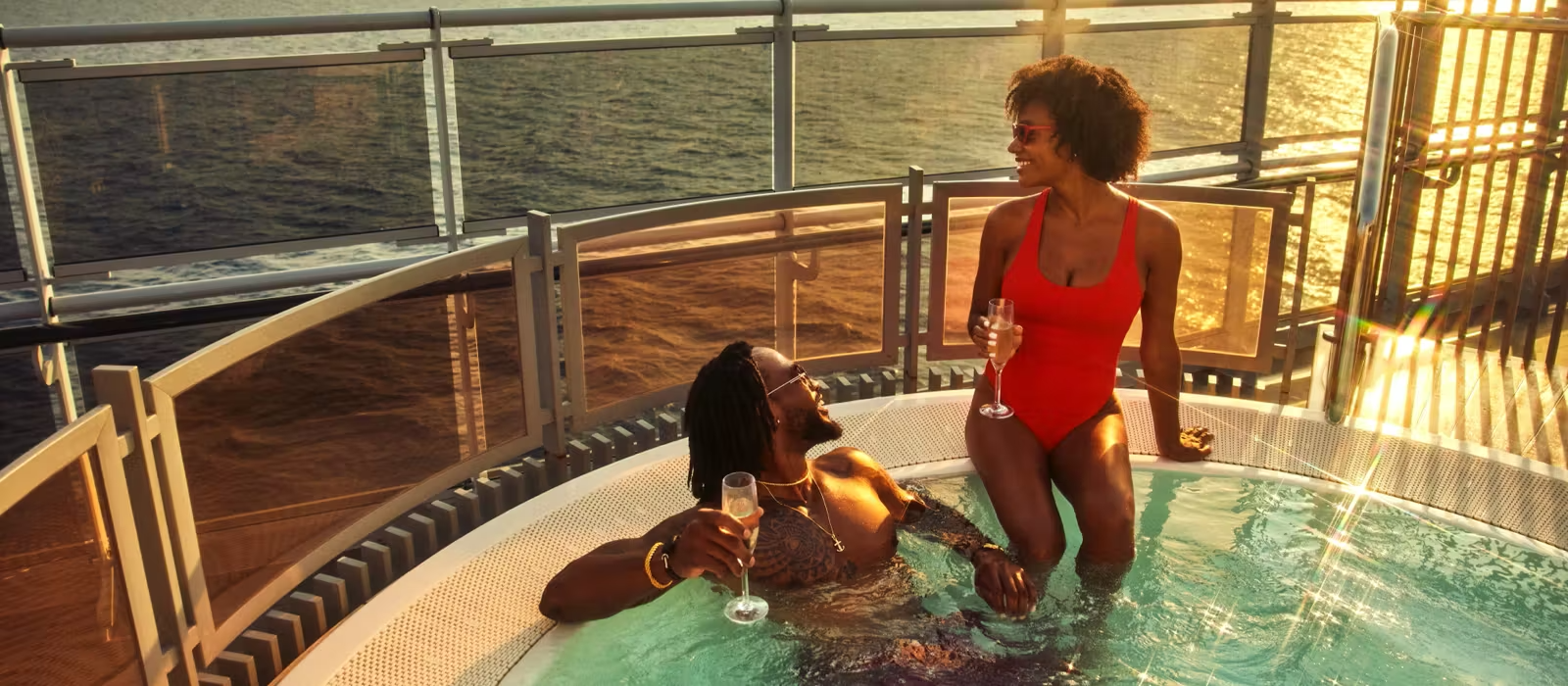 Virgin Voyages Brilliant Lady Sunset Pool Deck Two women enjoy champagne in a luxurious hot tub on the pool deck of Virgin Voyages' Brilliant Lady