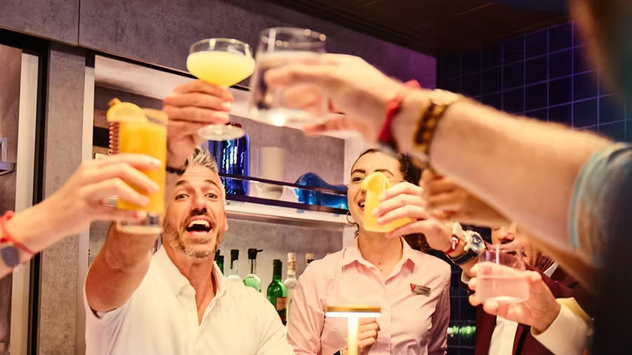Virgin Voyages Passengers Toasting with Cocktails A lively group of passengers aboard a Virgin Voyages cruise ship celebrating and toasting