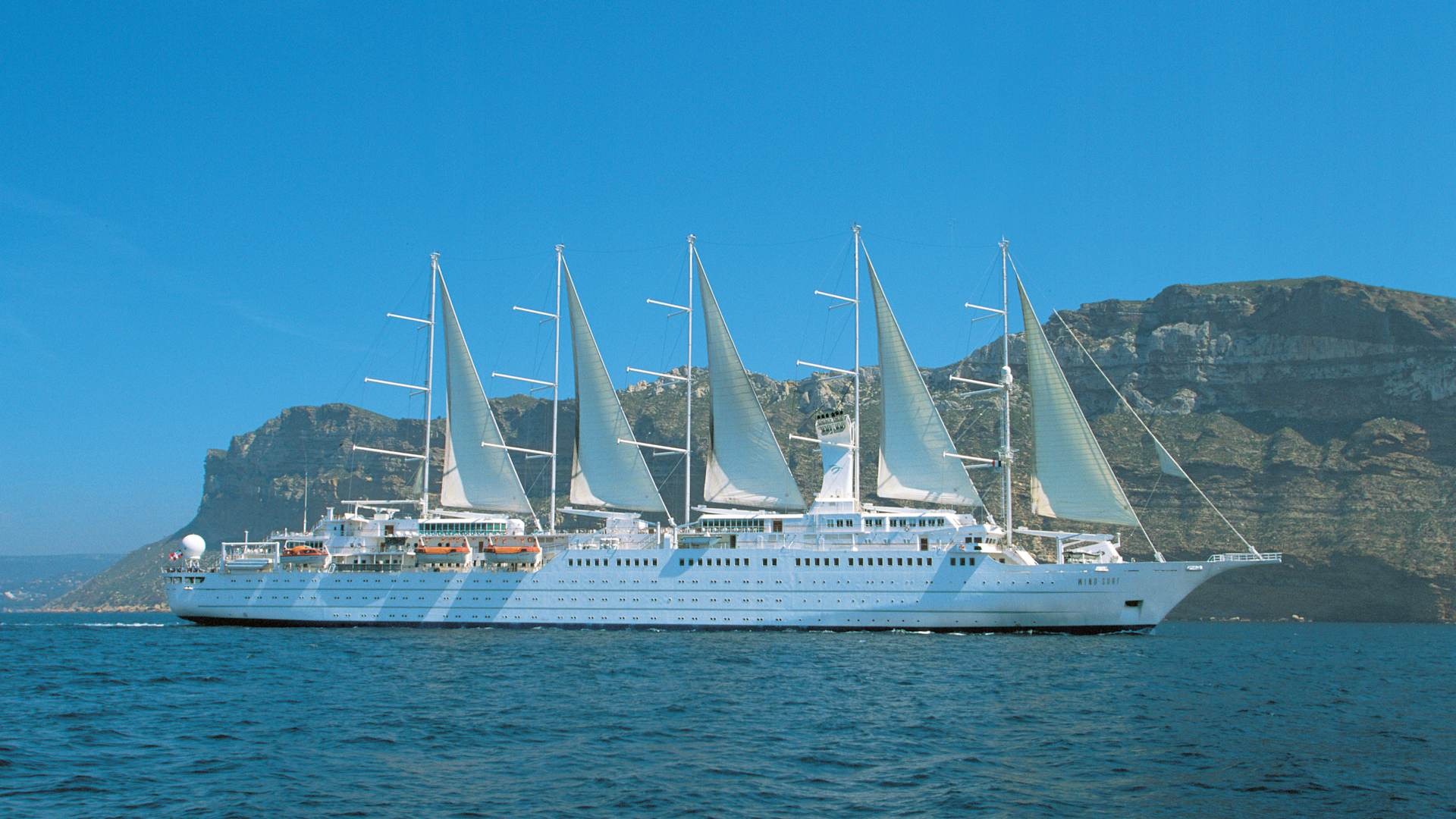 Windstar Cruises Luxury Sailing Ship at Anchor A striking luxury sailing cruise ship with five tall masts and billowing white sails is anchored